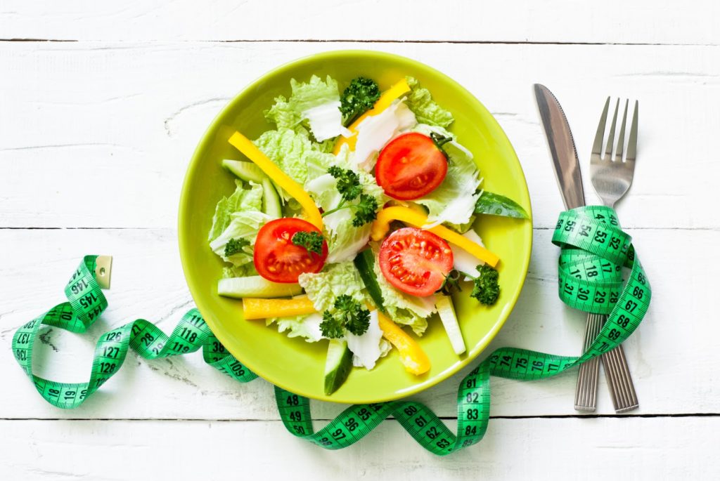 Healthy eating and Diet concept. Green Plate with fresh vegetables salad and measurement on wooden table.