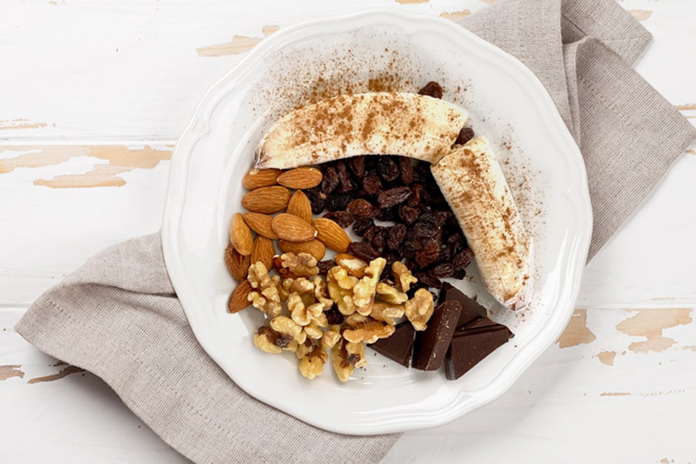 Dessert Plate With Bananas, Dried Plumbs, Almonds, and Chocolate.