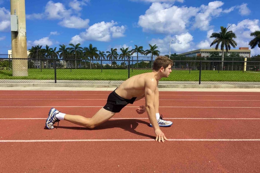 A Man Stretches His Legs on the Athlete Track.
